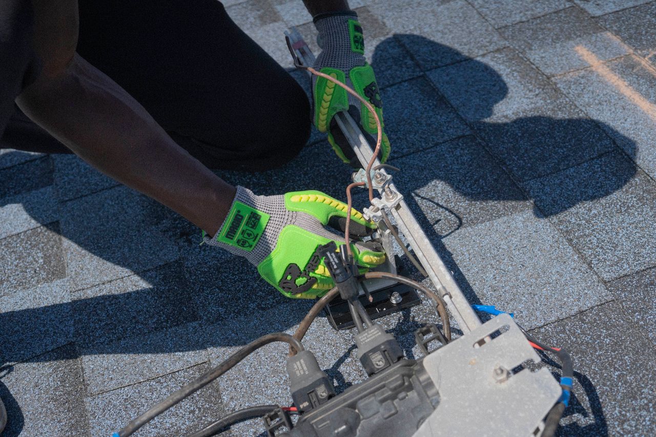 Close-up of a technician working on solar panel installation with green gloves in Tampa, Florida.